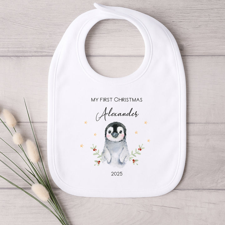 Baby bib with penguin design and text on a wooden surface