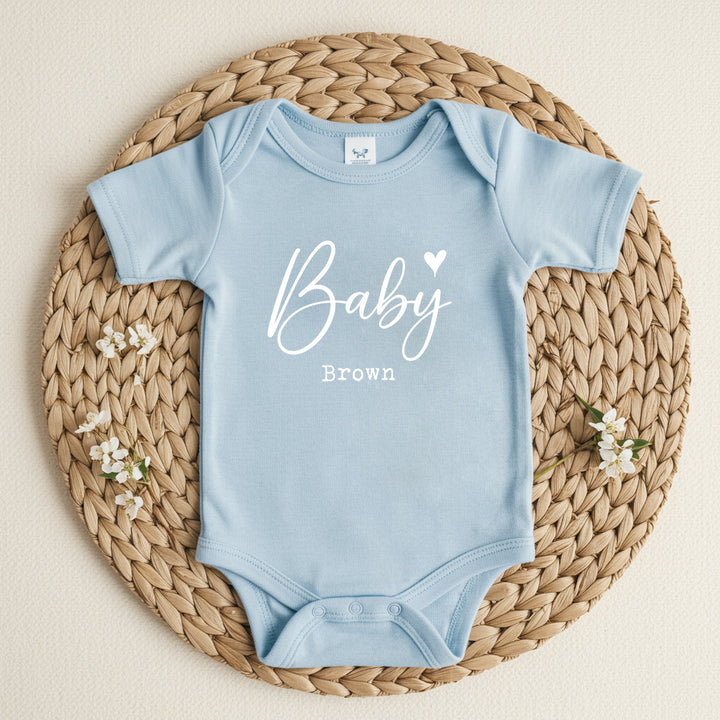 a personalised blue baby vest that says 'Baby Brown'