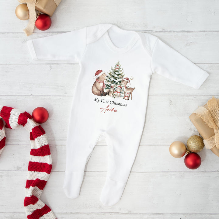 White baby onesie with Christmas design on a white wooden surface with festive decorations.