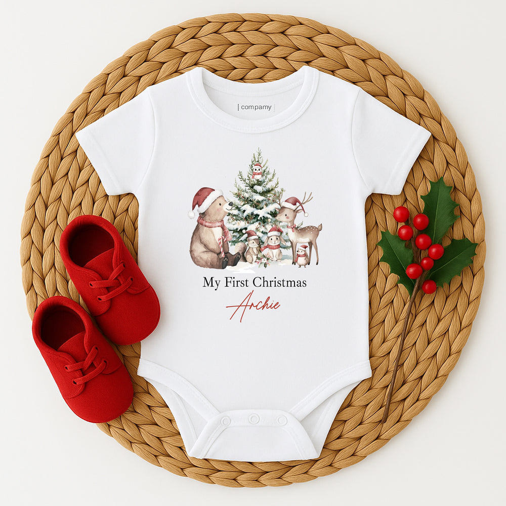 White baby onesie with Christmas design and red shoes on a woven mat