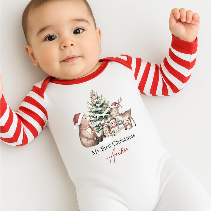Baby wearing a red and white striped onesie with Christmas design and text.
