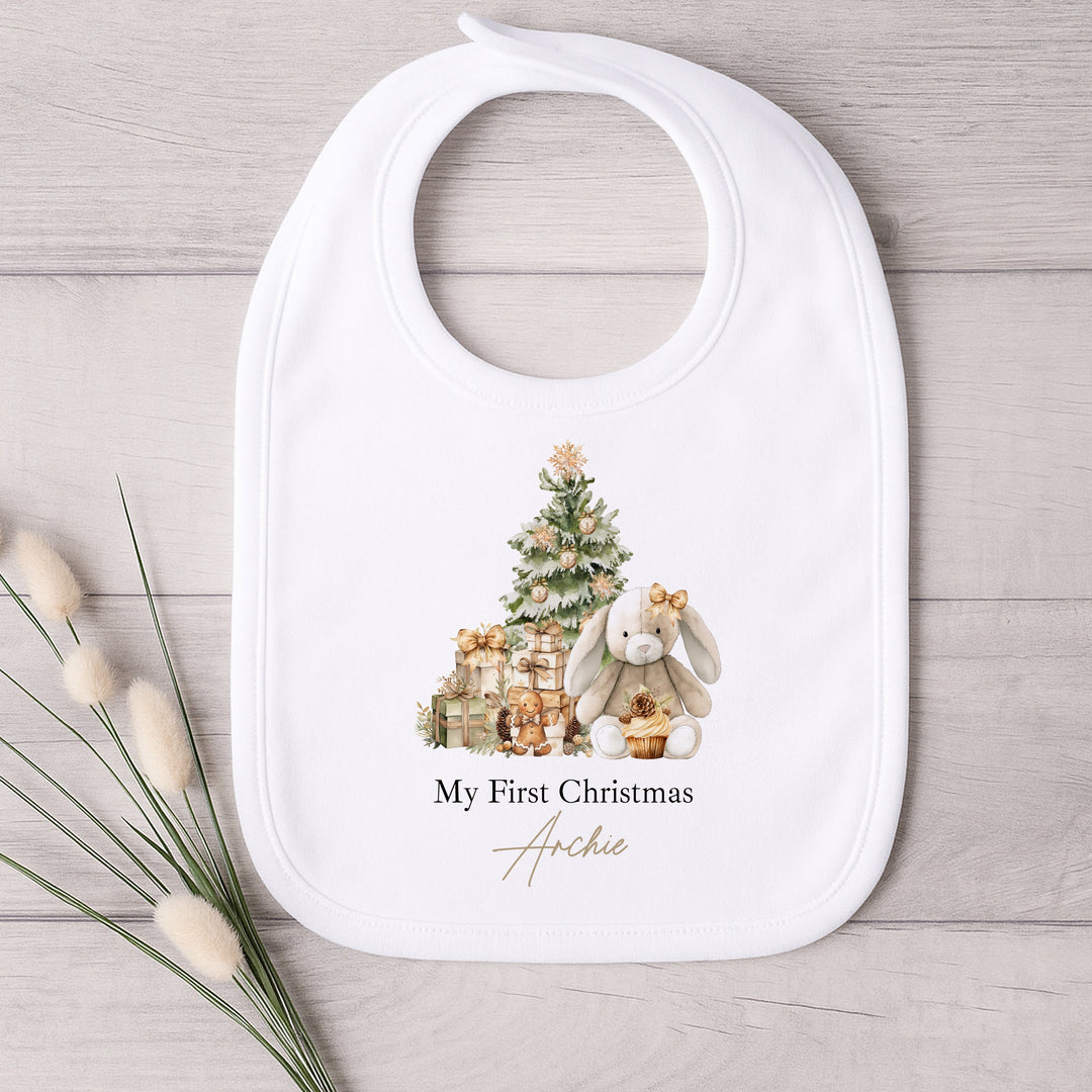 Baby bib with Christmas design and 'My First Christmas Archie' text on a wooden surface.