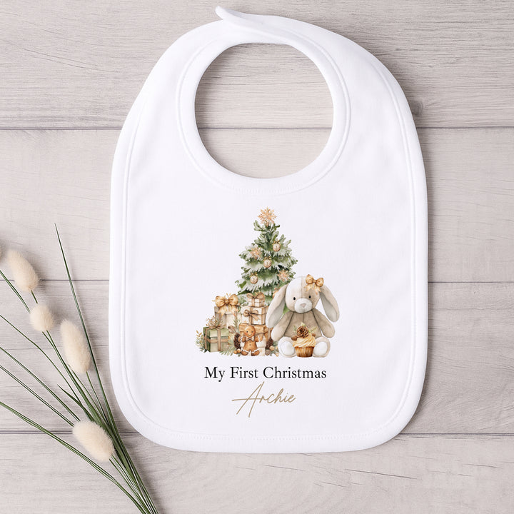 Baby bib with Christmas design and 'My First Christmas Archie' text on a wooden surface.