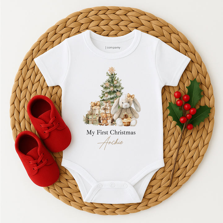 White baby onesie with Christmas design and red shoes on a woven mat