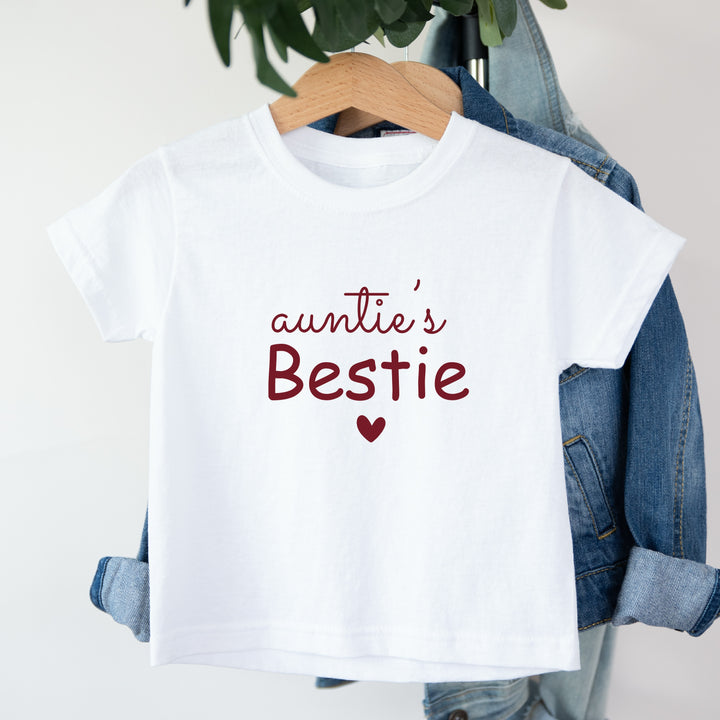 White t-shirt with 'auntie's Bestie' text and heart on a hanger with denim jacket.