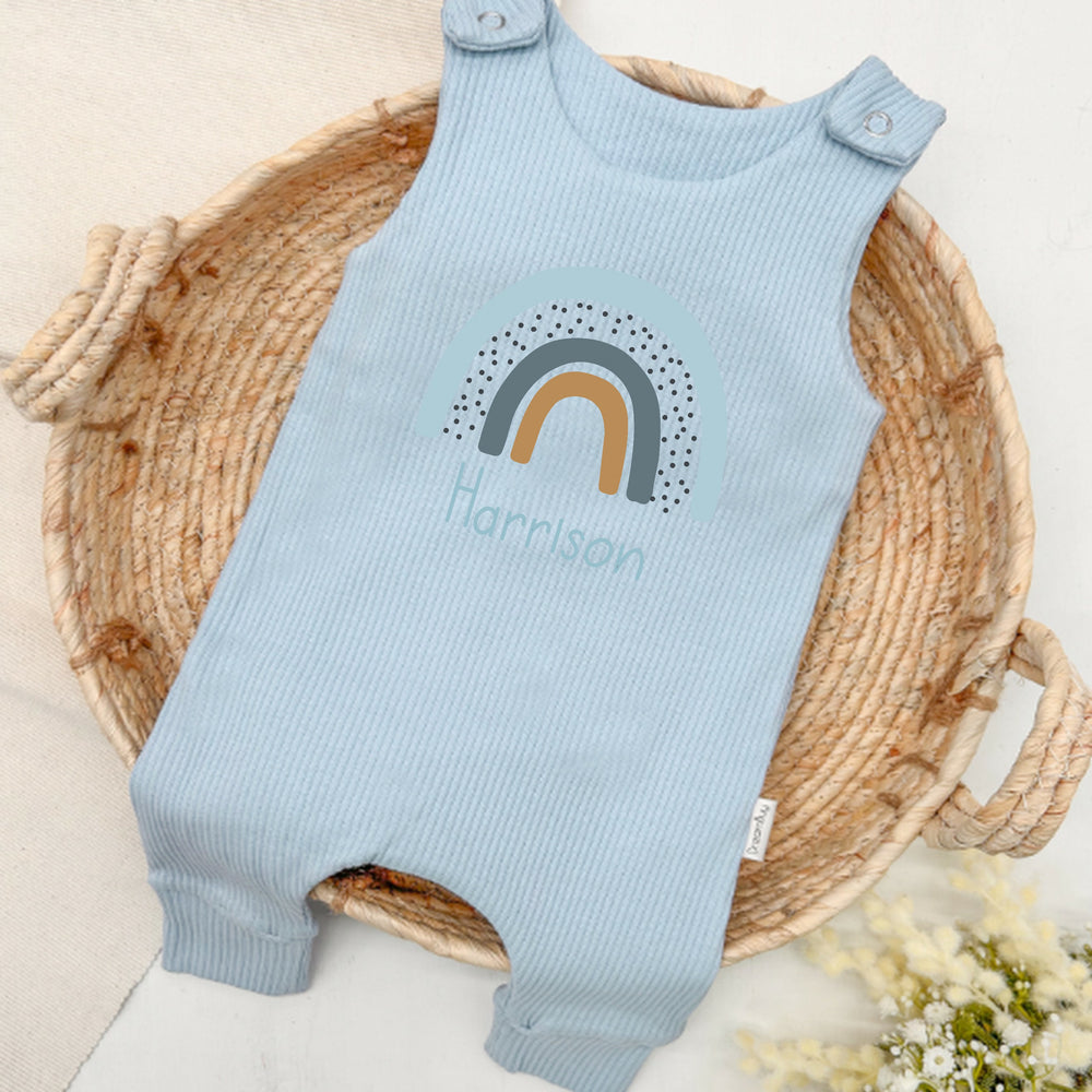Personalised blue ribbed dungarees that say 'Harrison'. This design features a blue rainbow
