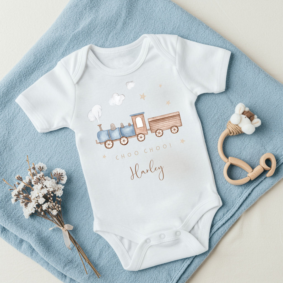 a personalised white baby vest that says 'Choo Choo! Harley'. This design features a blue steam train