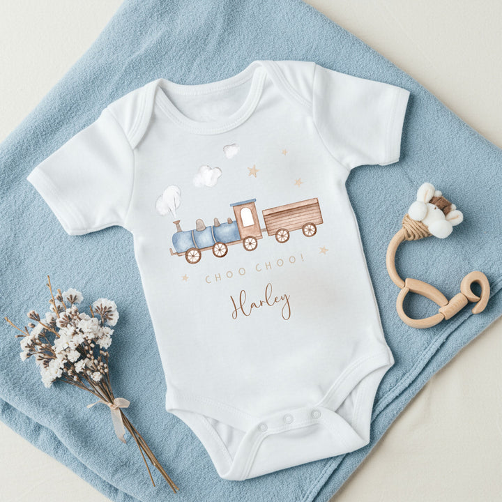 a personalised white baby vest that says 'Choo Choo! Harley'. This design features a blue steam train