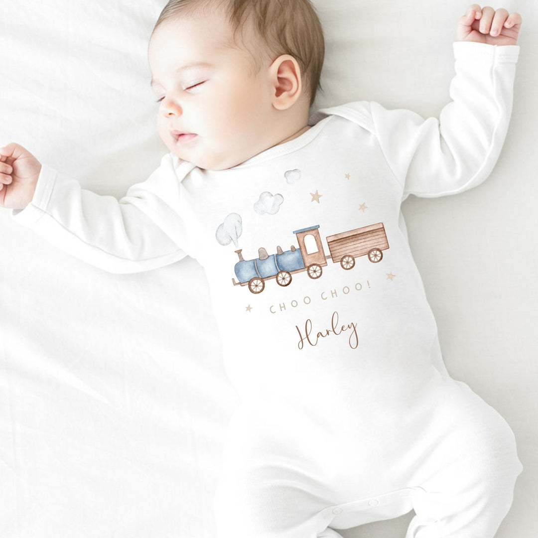 a personalised white baby grow that says 'Choo Choo! Harley'. This design features a blue steam train