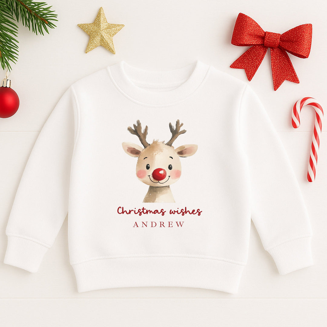 White hoodie with a reindeer design and 'Christmas wishes ANDREW' text, surrounded by Christmas decorations.