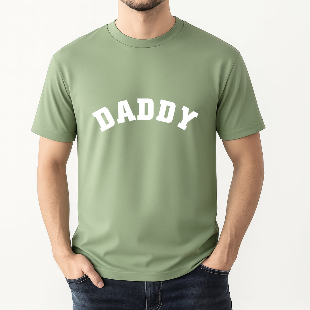 Person wearing a green t-shirt with 'DADDY' printed on it against a white background