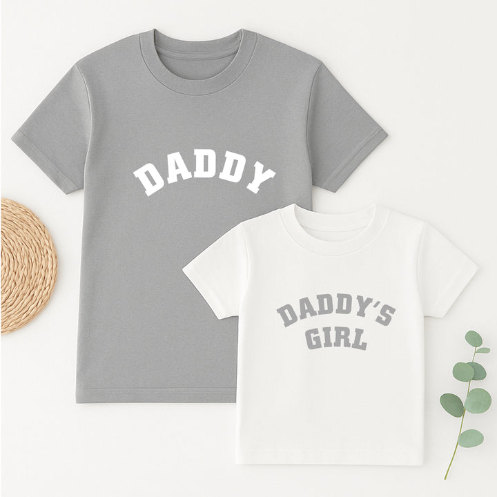 Gray t-shirt with 'DADDY' and white t-shirt with 'DADDY'S GIRL' on a light background