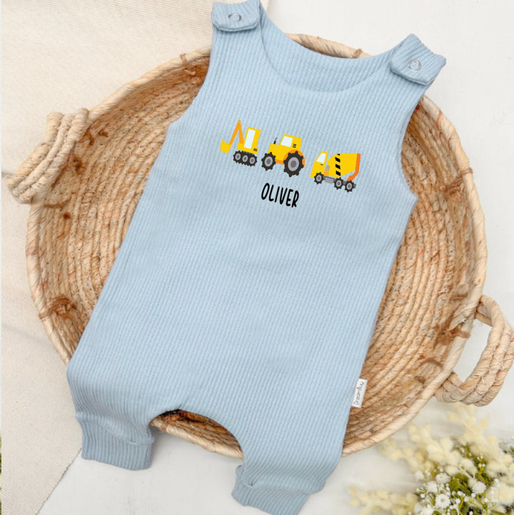 Personalised blue ribbed dungarees that say 'Oliver'. This design features 3 diggers