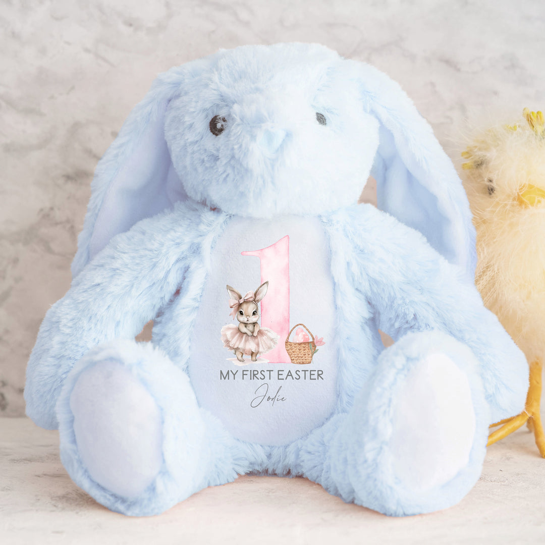 Personalised blue bunny Easter teddy that says 'My First Easter Jodie'. This design features a big pink 1 with a ballerina bunny one side and an Easter basket with pink eggs in it on the other side.