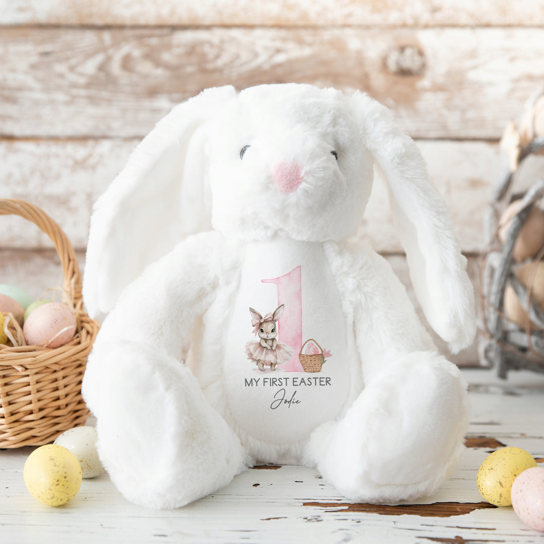 Personalised white bunny Easter teddy that says 'My First Easter Jodie'. This design features a big pink 1 with a ballerina bunny one side and an Easter basket with pink eggs in it on the other side.