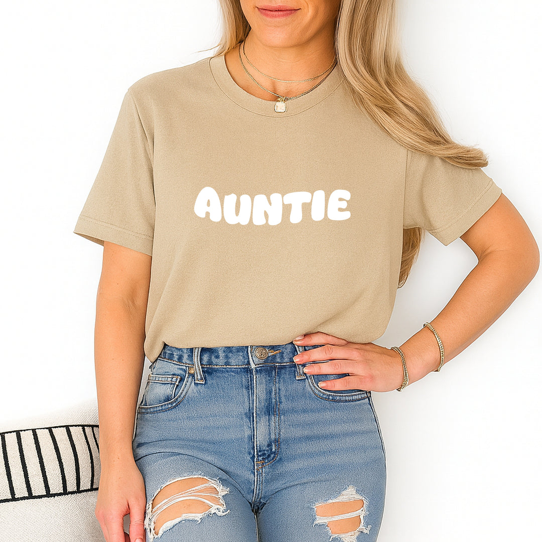 Person wearing a beige t-shirt with 'AUNTIE' printed on it and ripped blue jeans.