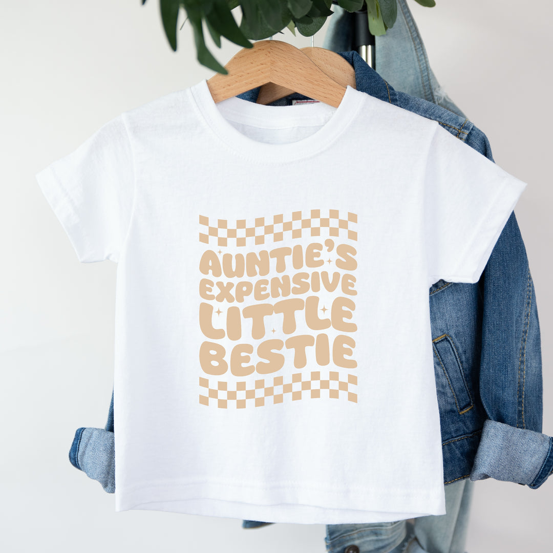 White t-shirt with text and checkered design on a hanger with denim jacket