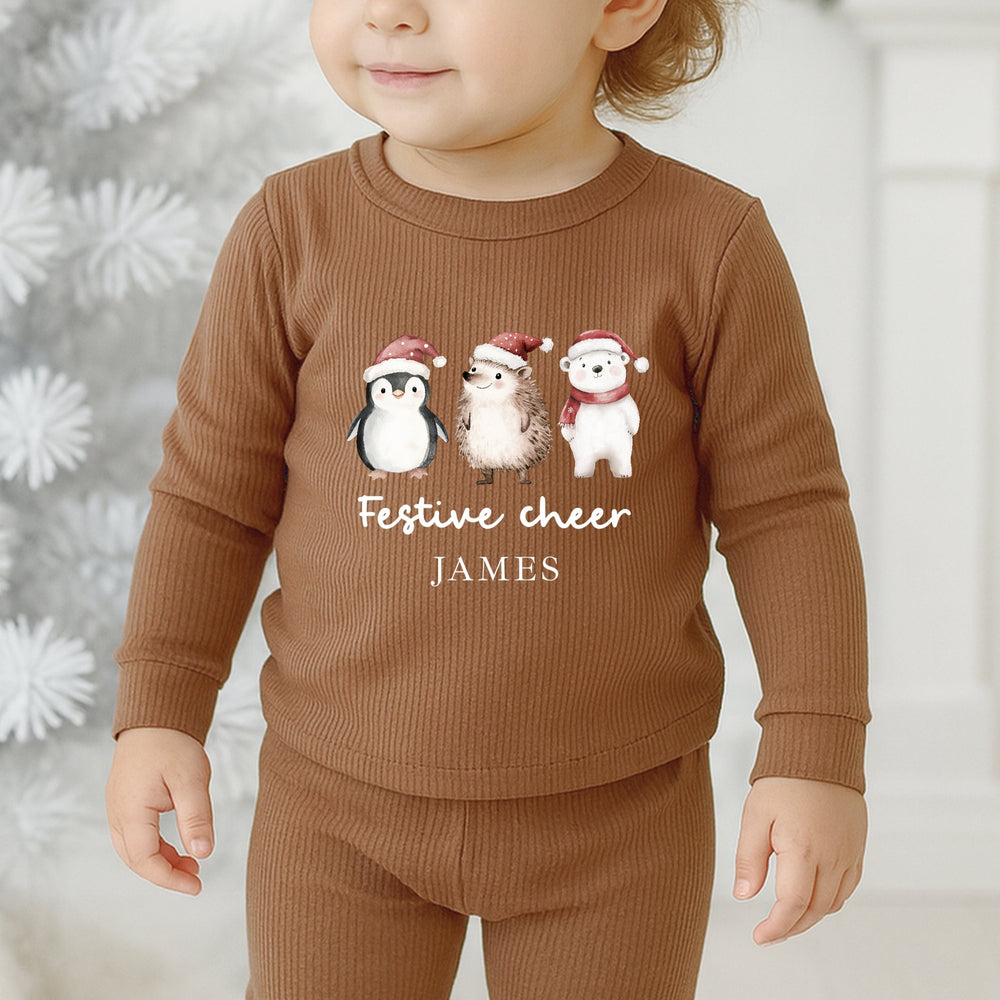 Child wearing a brown outfit with festive designs and text in front of a Christmas tree.