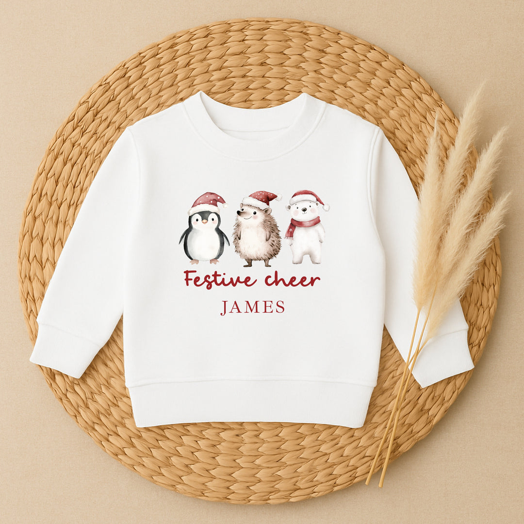 White sweatshirt with penguin, hedgehog, and polar bear design on a woven mat.