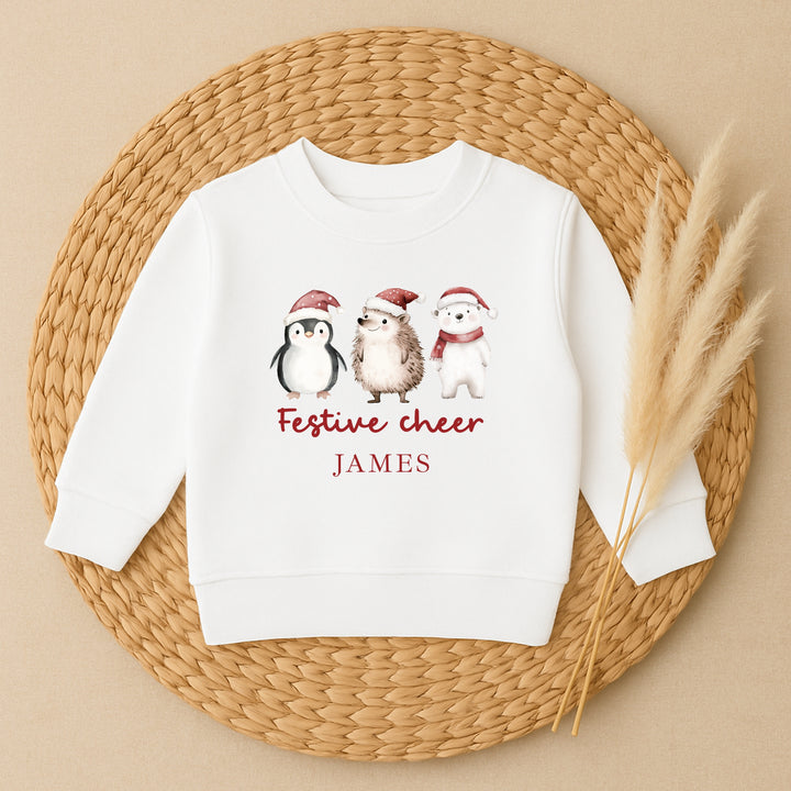 White sweatshirt with penguin, hedgehog, and polar bear design on a woven mat.