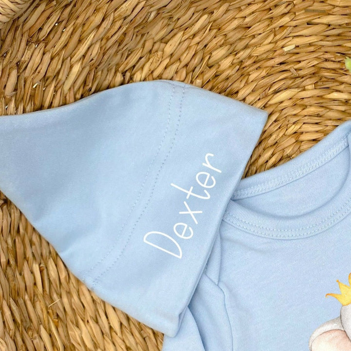 a personalised blue baby hat that says 'Dexter'. This design features an elephant wearing a crown