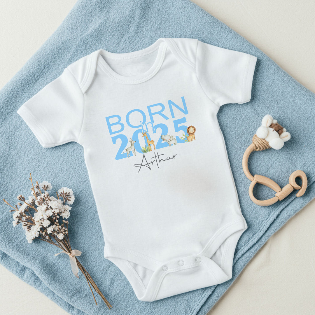 a personalised white baby vest that says 'Born in 2025 Arthur'. This design features safari animals