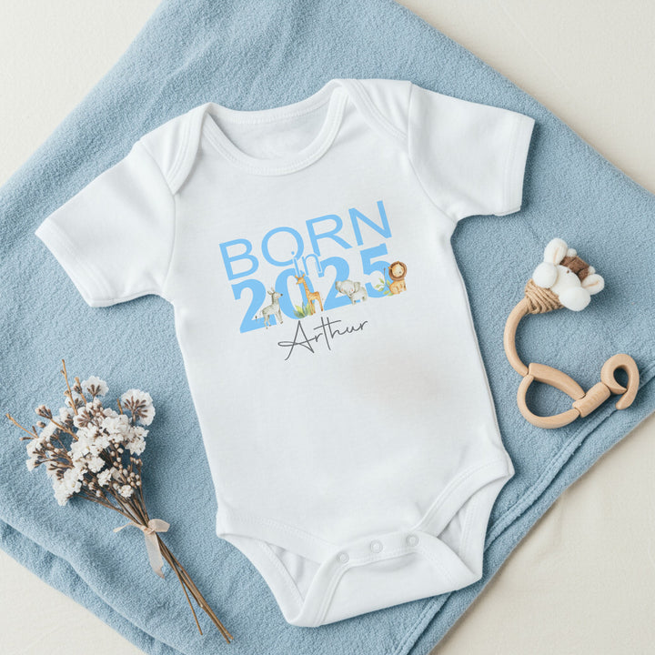 a personalised white baby vest that says 'Born in 2025 Arthur'. This design features safari animals