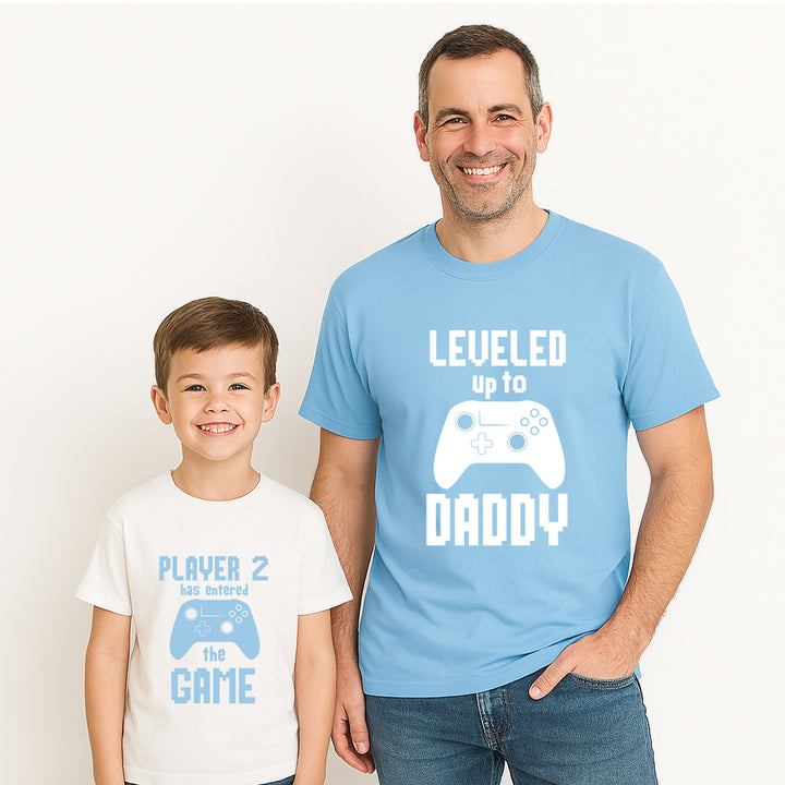 Man and child wearing matching t-shirts with gaming-themed text on a white background
