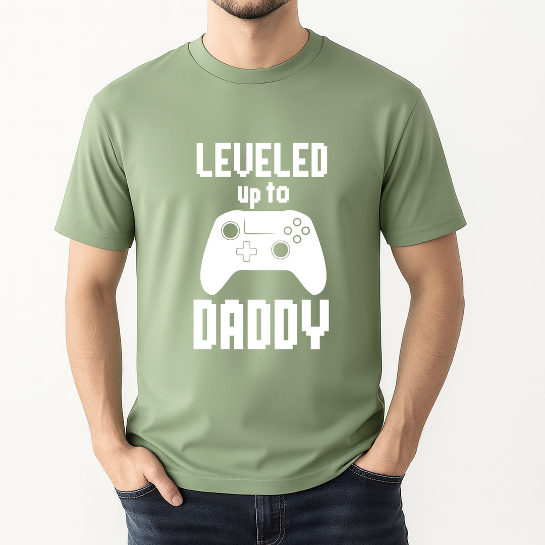 Person wearing a green t-shirt with 'Leveled up to Daddy' text and game controller graphic.