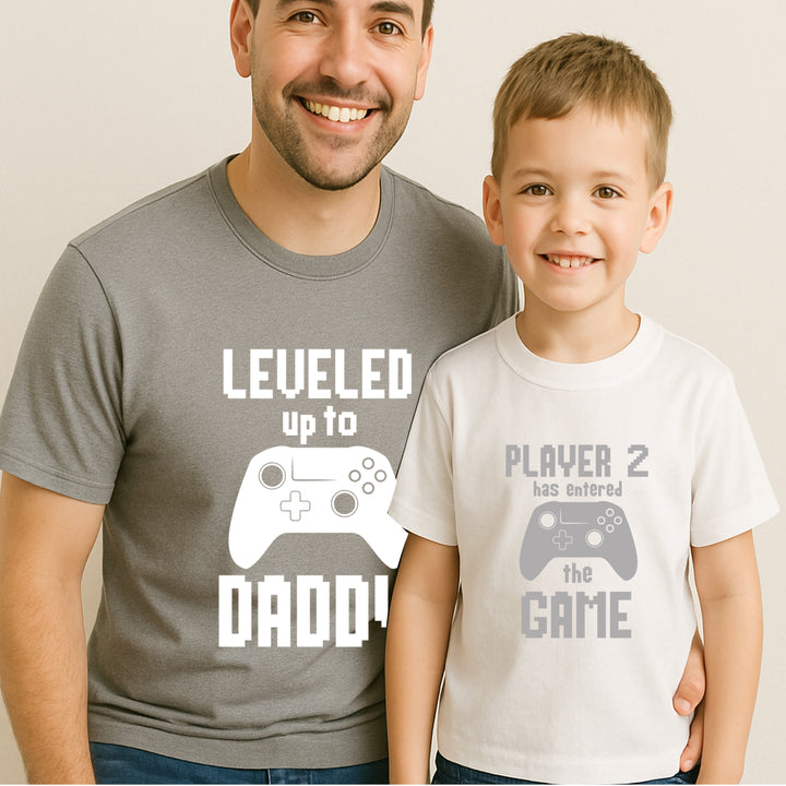 Man and child wearing matching t-shirts with gaming-themed text and graphics.