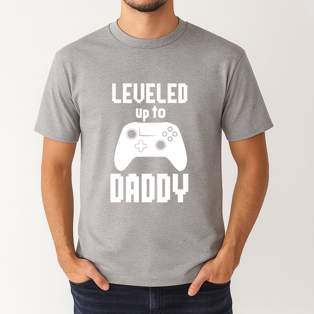 Gray t-shirt with 'Leveled up to Daddy' text and gaming controller graphic on a white background