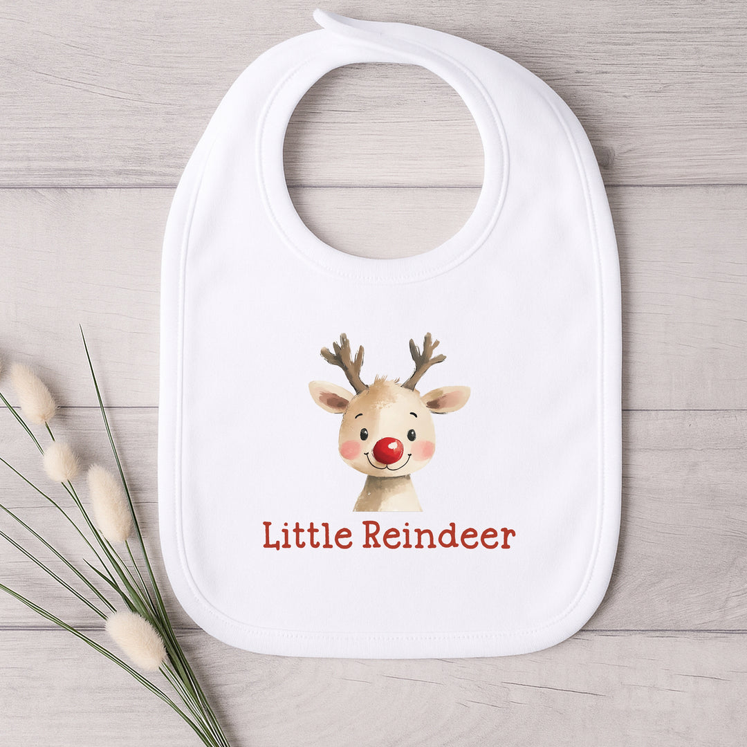 White bib with a reindeer design and 'Little Reindeer' text on a wooden surface.