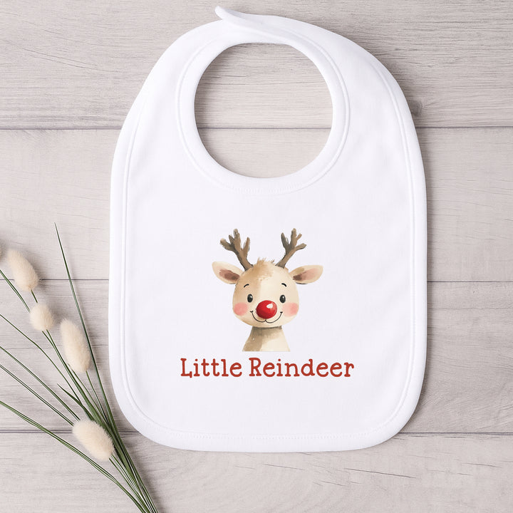 White bib with a reindeer design and 'Little Reindeer' text on a wooden surface.