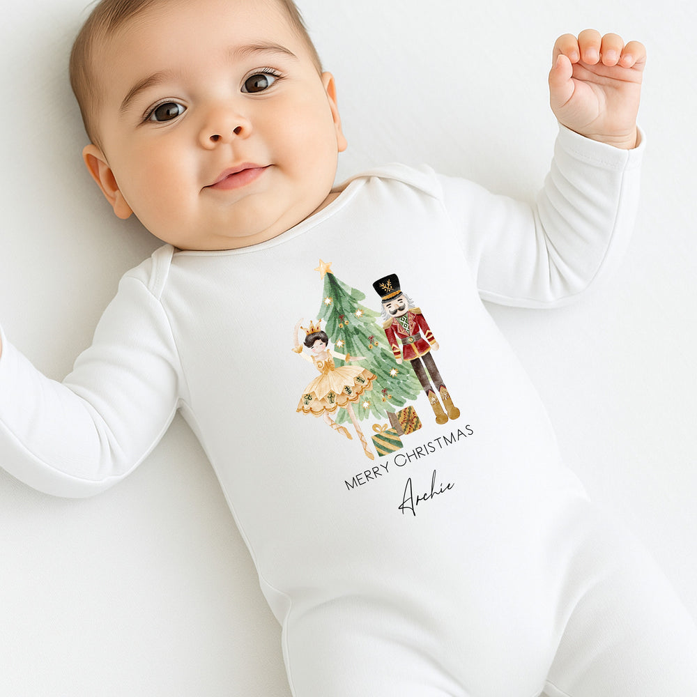 Baby wearing a white onesie with Christmas design and text