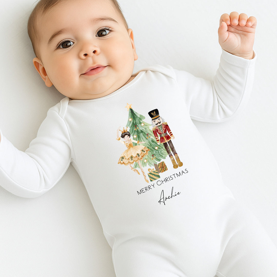 Baby wearing a white onesie with Christmas design and text