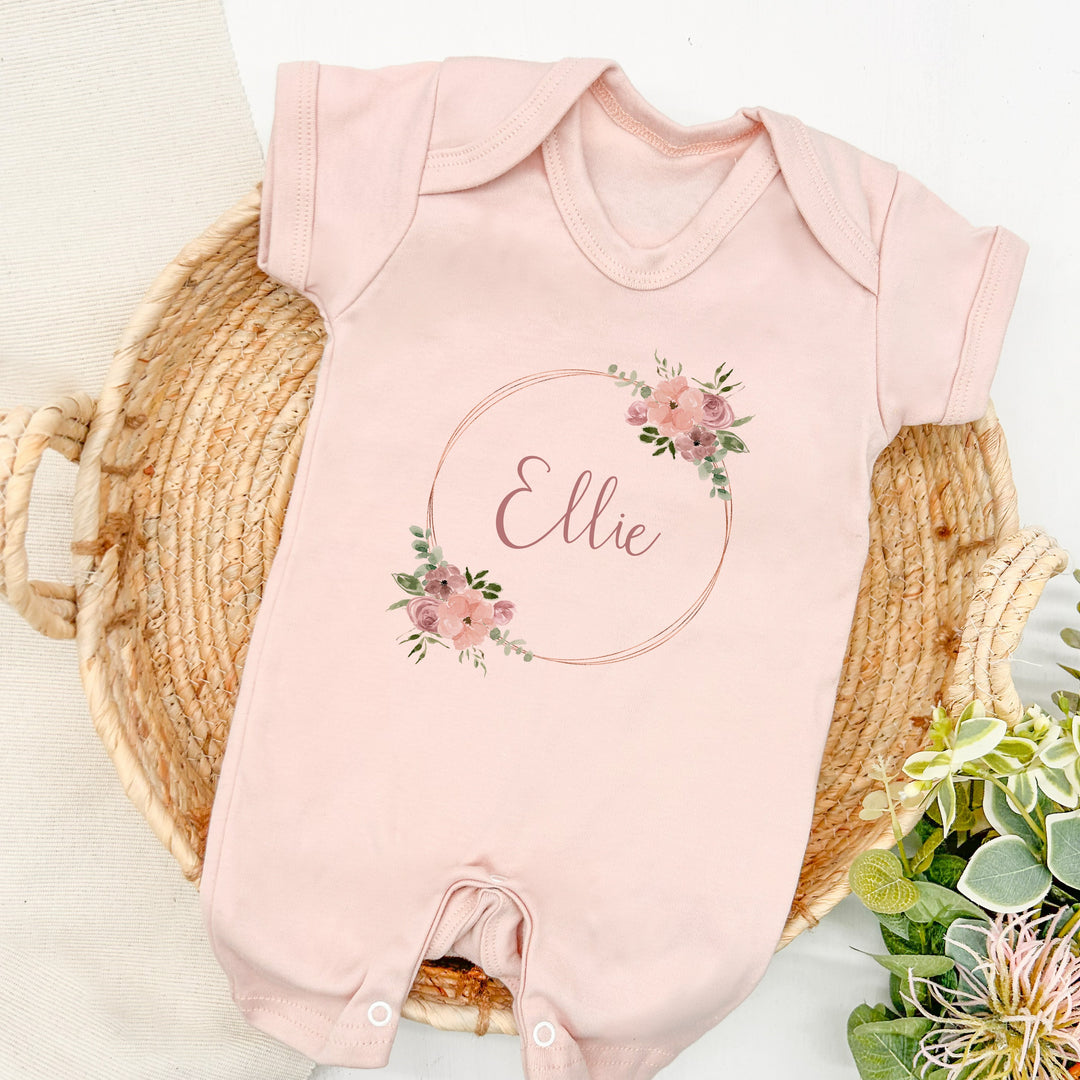 a personalised pink baby romper that says 'Ellie'. This design that features a pink and gold floral wreath
