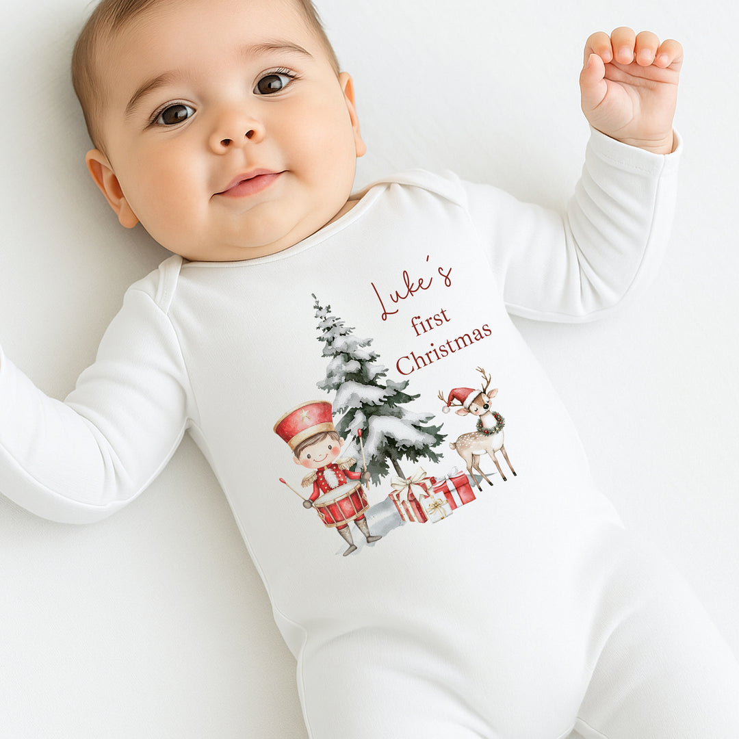 Baby wearing a 'Luke's first Christmas' onesie with Christmas-themed graphics.