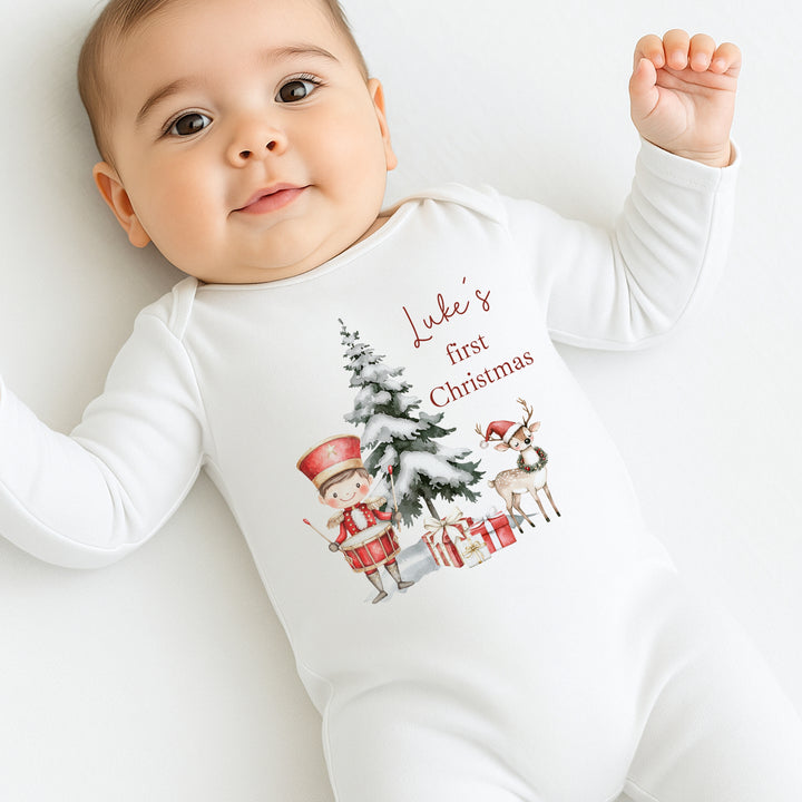 Baby wearing a 'Luke's first Christmas' onesie with Christmas-themed graphics.