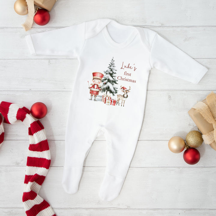 Baby onesie with Christmas design on a white wooden surface with festive decorations.