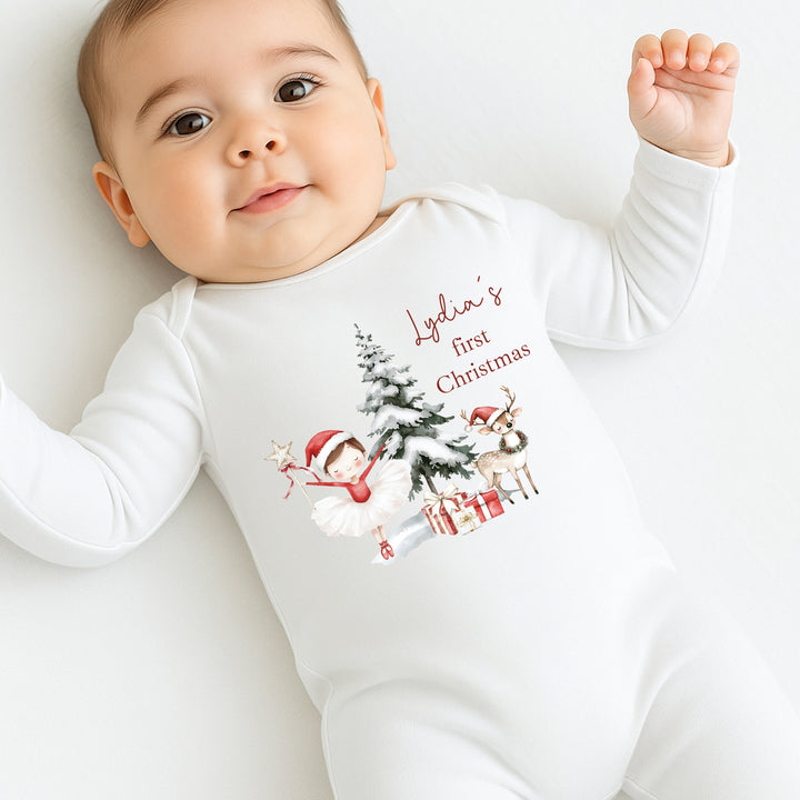 Baby wearing a white onesie with Christmas-themed design and text on a white background