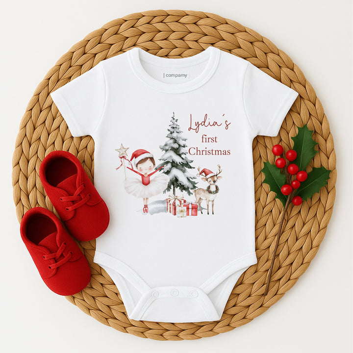 Baby onesie with Christmas design and red shoes on a woven mat