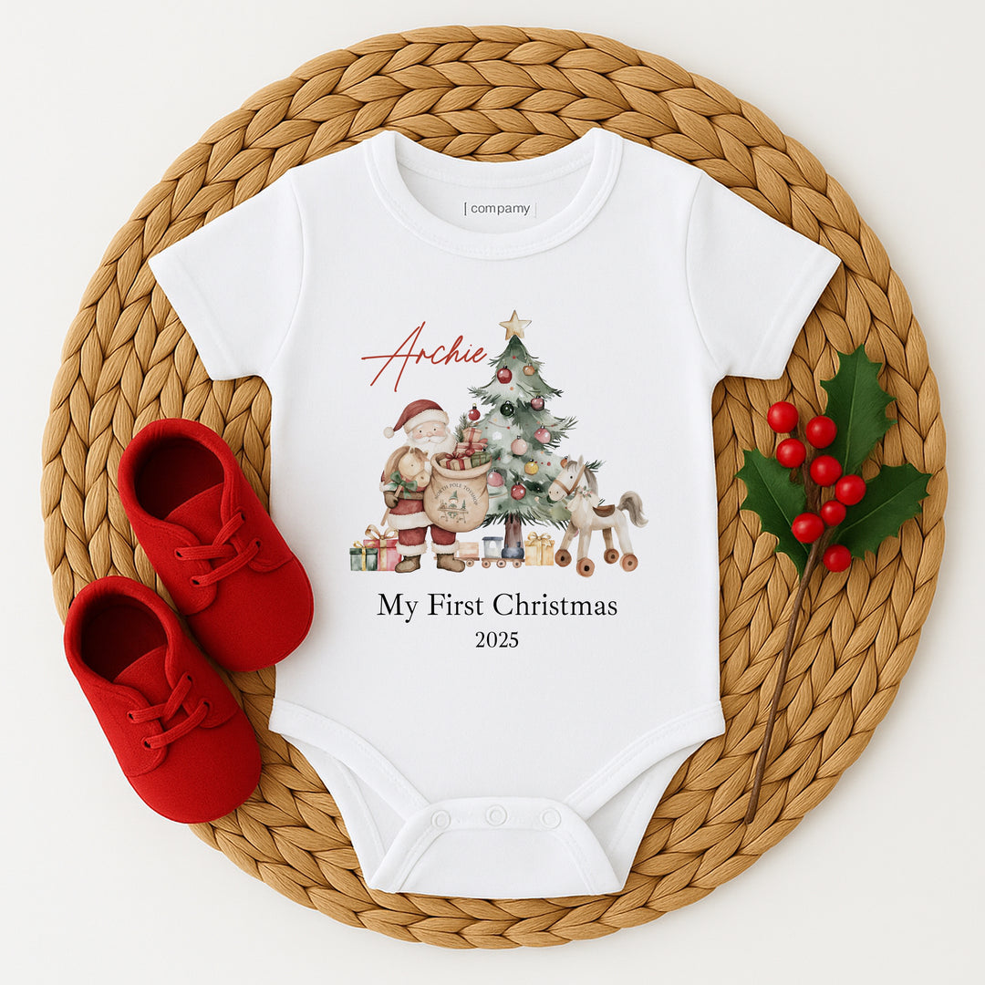 White baby onesie with Christmas design and red shoes on a woven mat