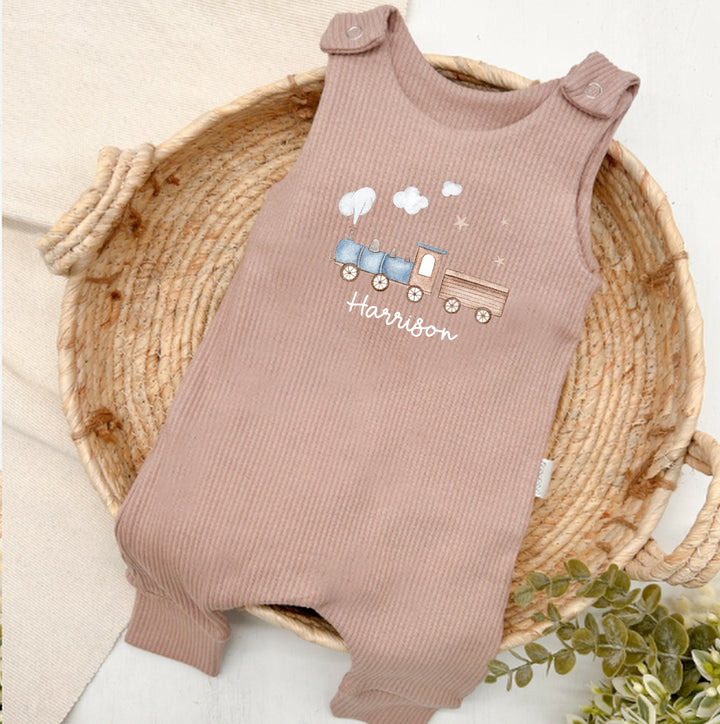Personalised brown ribbed dungarees that say 'Harrison'. This design features a blue train