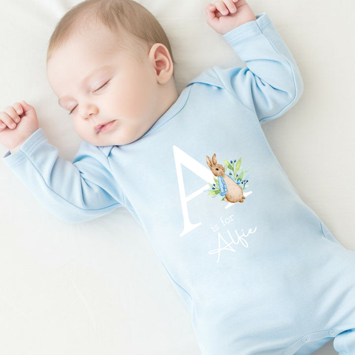 a personalised blue baby grow that says 'A is for Alfie'. This design features a rabbit wearing a blue jacket
