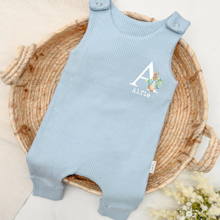Personalised blue ribbed dungarees that say 'Alfie'. This design features a rabbit wearing a blue jacket