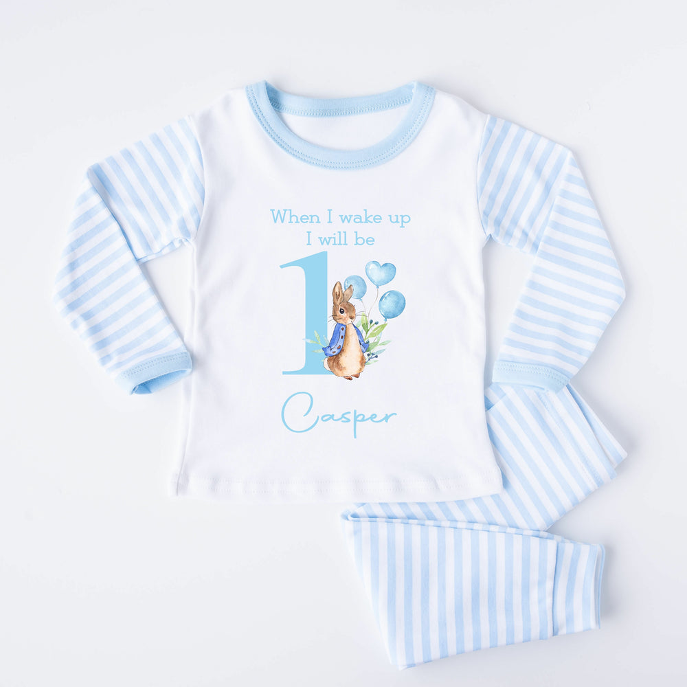 Blue Stripe pyjamas that say: When I Wake up I will be 1 Casper with a rabbit in a blue jacket holding balloons next to the number 1.