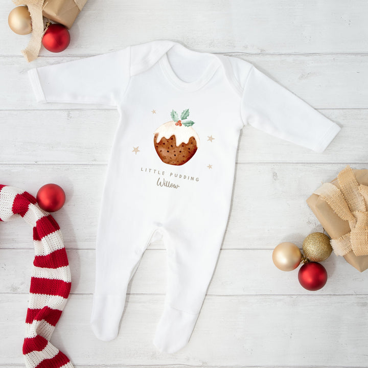 White baby onesie with festive design on a white wooden surface with Christmas decor.