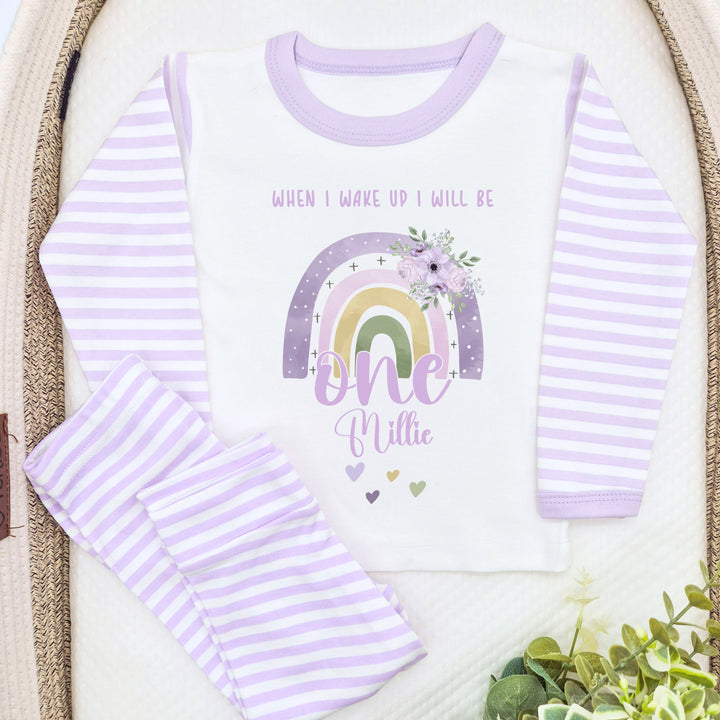 A pair of lilac and white stripe children's birthday pyjamas with a purple floral rainbow design saying "When I wake up I will be one" with the name "Millie".