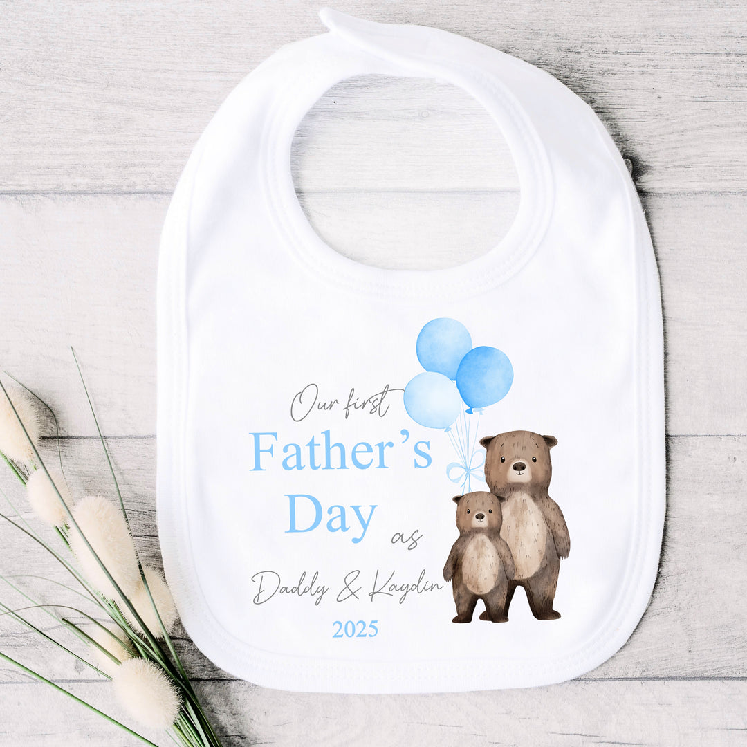 Personalised white Father's Day baby bib that says 'Our First Father's Day as Daddy & Kaydin 2025'. This design features 2 brown bears holding 3 blue balloons