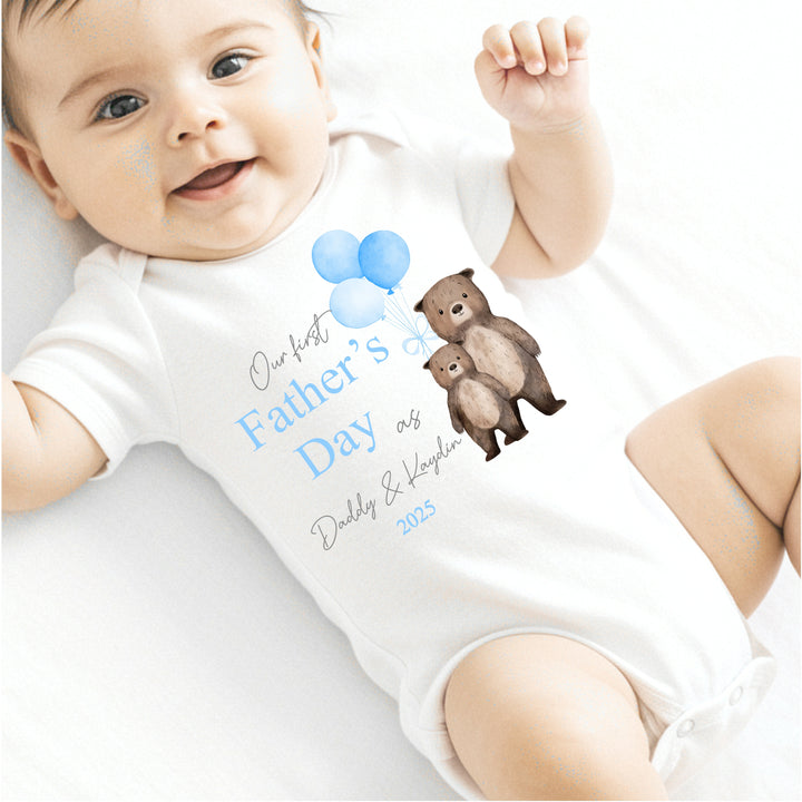 Personalised white Father's Day baby vest that says 'Our First Father's Day as Daddy & Kaydin 2025'. This design features 2 brown bears holding 3 blue balloons